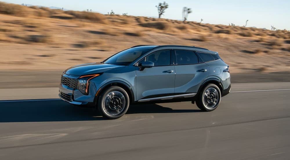 A blue 2026 Kia Sportage driving on a highway.
