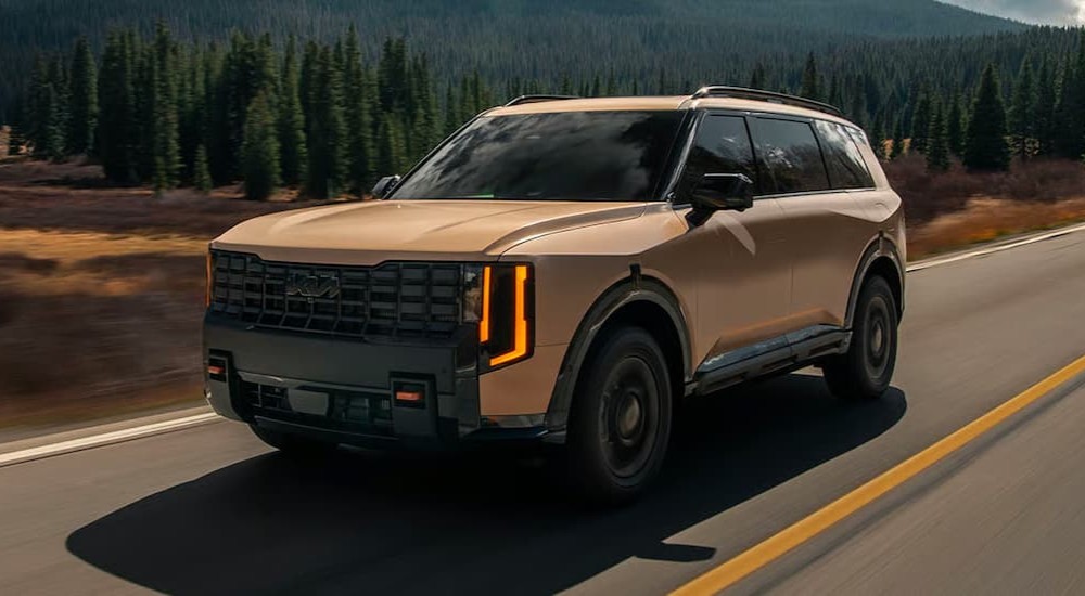 A bronze 2027 Kia Telluride driving on a highway.