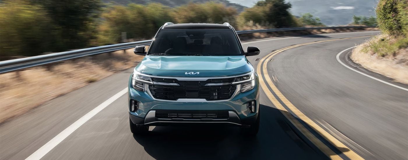 Blue 2026 Kia Seltos front view driving on a road.