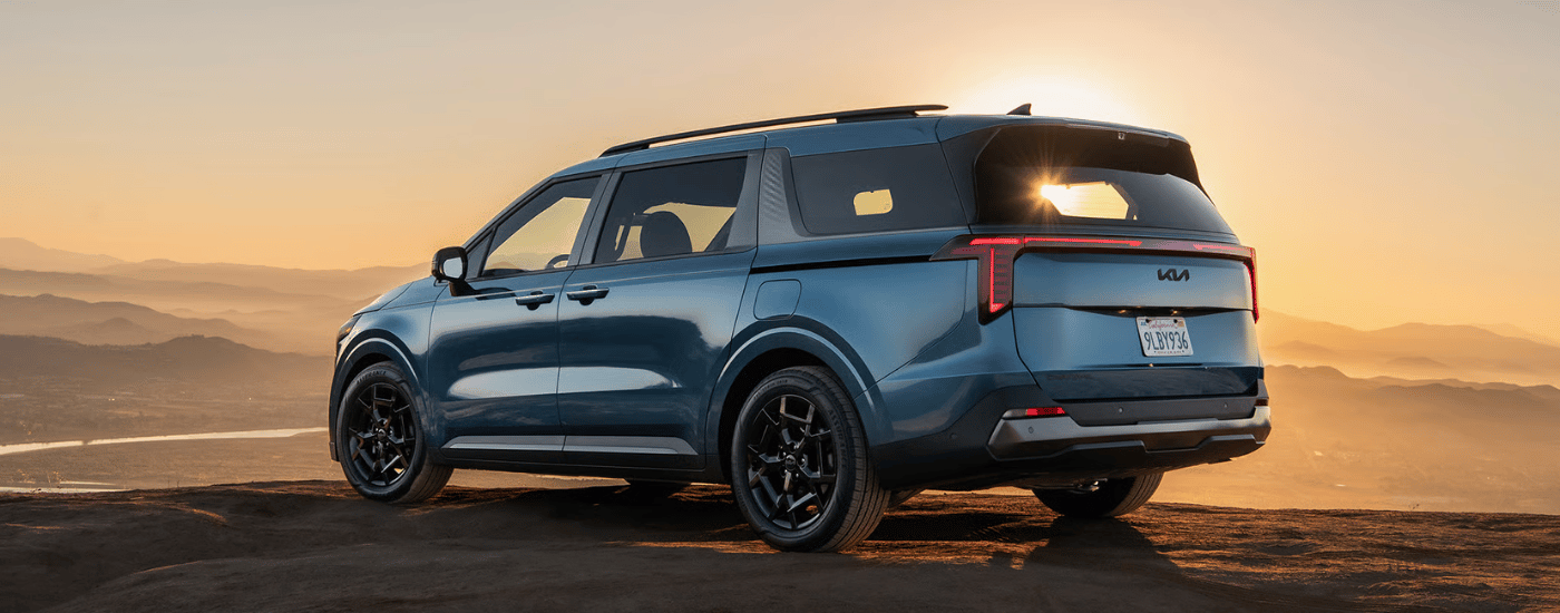 Rear look at a blue 2026 Kia Carnival parked at an angle