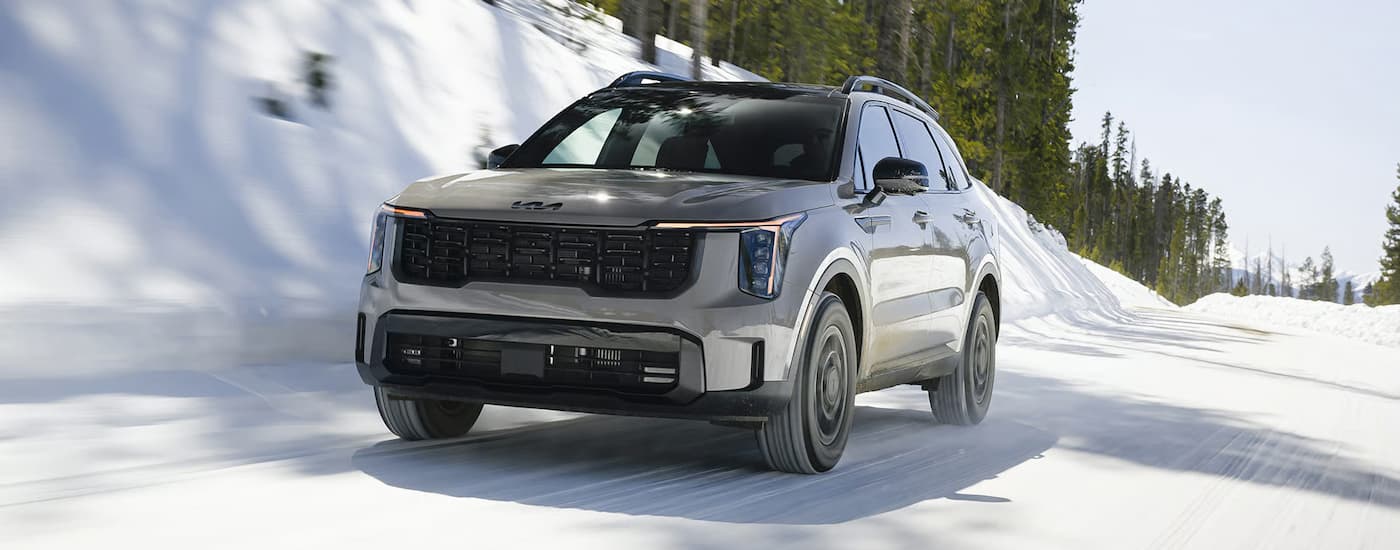 Grey 2026 Kia Sorento driving down a snowy road.