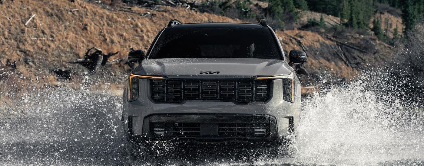 Grey 2026 Kia Sorento driving over a shallow river.