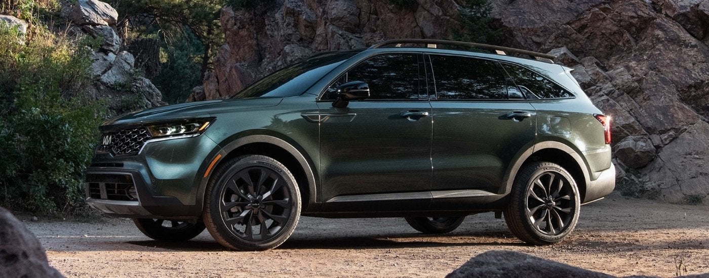 A green 2022 Kia Sorento X-Line parked by a rock wall.